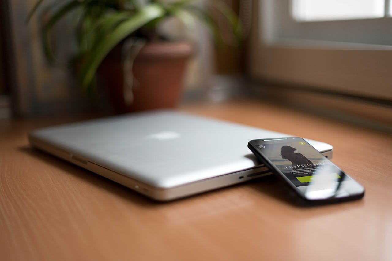 About Close-up of a silver laptop and smartphone on a wooden desk, capturing modern work essentials.
